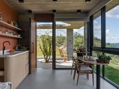 A modern kitchen with wooden finishes and a view of the outdoors through large windows.