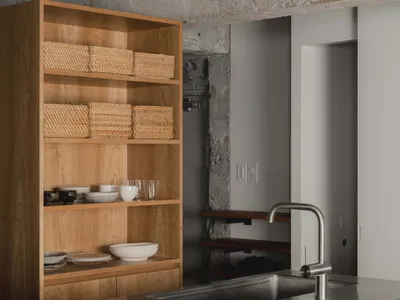 A minimalist residential kitchen featuring wooden cabinets and concrete countertops.