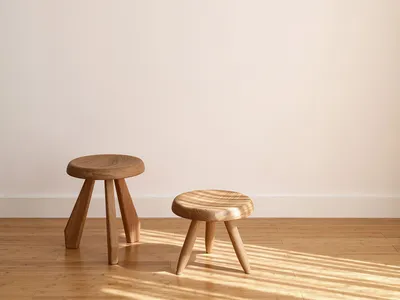 A minimalist wooden stool with three legs in a Scandinavian style setting.
