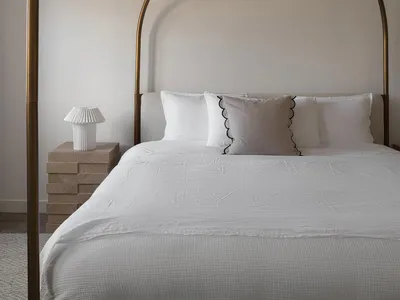A minimalist bedroom with a brass headboard and fabric cushions