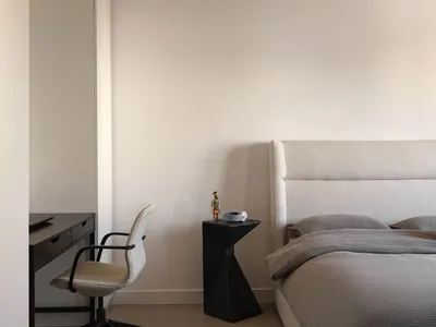 Minimalist bedroom featuring white fabric furniture and a cozy, neutral color palette.