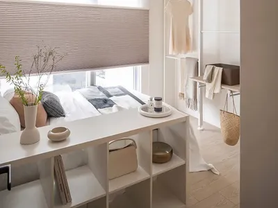 A minimalist bedroom with wooden furnishings, a bed, a desk, and organized closet space.