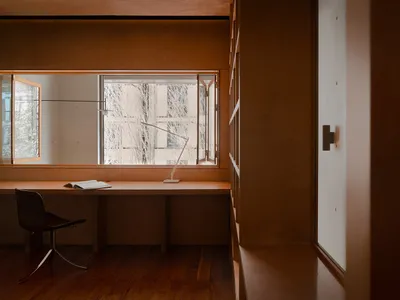 A modern home office featuring wooden paneled walls and furniture, with a desk, chair, and lamp.
