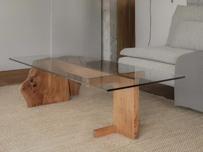 Modern industrial interior living room with glass table, wooden elements, and concrete walls.
