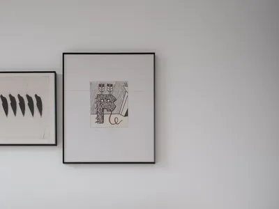 Modern minimalist bedroom featuring a yellow upholstered headboard against a white wall, with framed art hanging above a bed