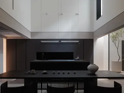 A modern kitchen features sleek concrete countertops and black metal cabinets.