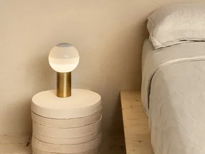 A minimalist bedroom featuring a concrete bedside table and lamp.