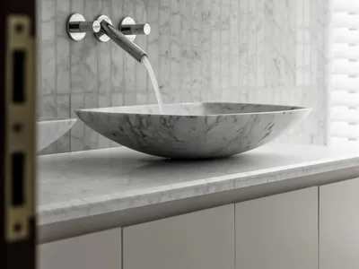 A minimalist bathroom with a marble countertop featuring a sleek, modern sink and faucet.