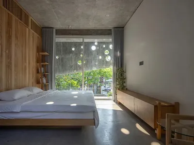 Minimalist bedroom with wood and concrete design elements and a blurred tree view through the window.