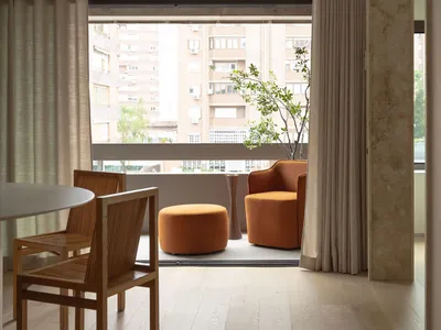 Modern minimalist living room with beige curtains, light wood flooring, and terracotta upholstered furniture.