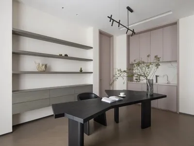 Modern home office with black wood table, minimalist design, and white shelves.