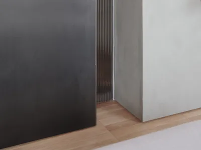 A modern minimalist bedroom with concrete walls and flooring.