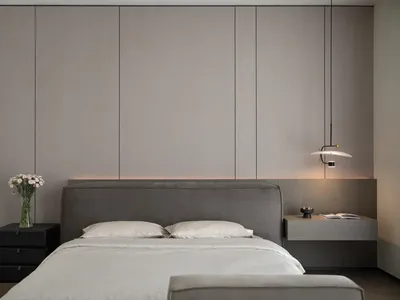 A modern bedroom with a grey upholstered bed and minimalist design elements.