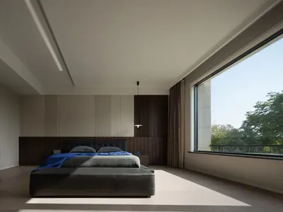 A minimalist bedroom with a large bed, wooden headboard, and floor-to-ceiling windows.