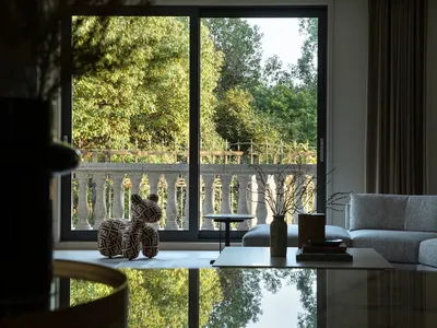Minimalist living room with furniture, a coffee table, and a view of the outdoors through large windows.
