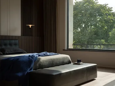Modern bedroom with fabric bedding, wooden headboard, and metallic floor lamp.
