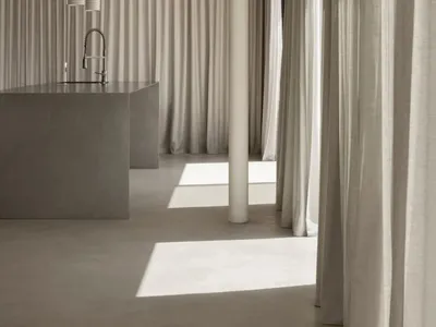 Modern minimalist kitchen with concrete elements and white curtains.