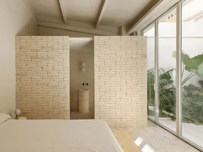 Modern minimalist bedroom with brick walls and natural light.
