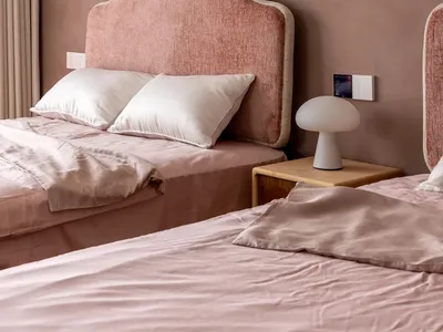 A minimalist bedroom with pink upholstered headboards and pink bedding on a bed with white pillows.