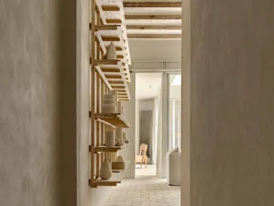 A minimalist living room with concrete walls and wooden shelves.