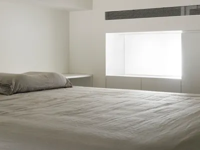 Modern minimalist bedroom featuring textured concrete surfaces and natural light.