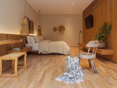 A minimalist bedroom featuring wooden furnishings, including a bed, chair, and hanging lamps.