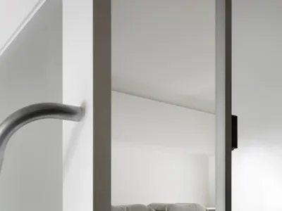 A minimalist bedroom featuring a wooden bed frame and grey bedding on a white bed sheet.
