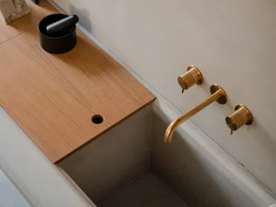 Modern kitchen featuring a wooden countertop, concrete sink, and brass faucet