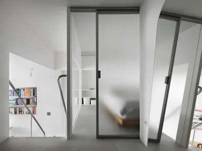 Modern minimalist bedroom with frosted glass doors and white interior design.