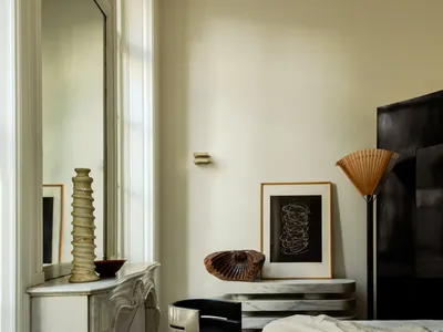Modern, minimalist bedroom with white marble fireplace, metal furnishings, and wooden floors.