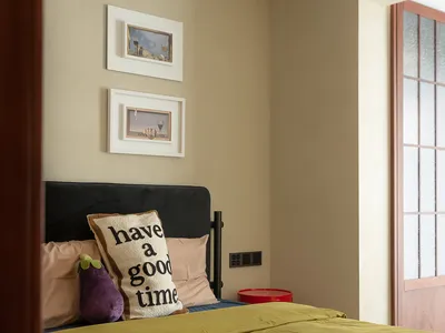 A minimalist bedroom with a green bedspread and a pillow that says 'have a good time'.