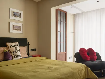 A modern bedroom featuring a comfortable bed with a pillow, eggs, and a red beanbag, and a cozy lounge area with a chaise lou