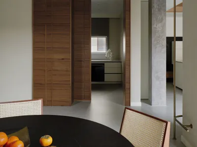 A minimalist kitchen with wooden cabinets, white marble countertops, and stainless steel appliances.
