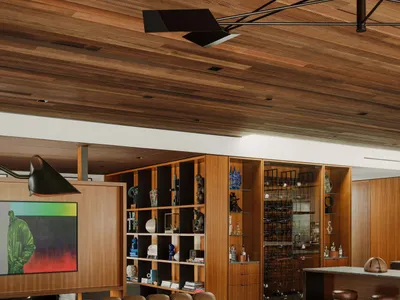 A modern, industrial living room with a round marble table, brown leather furniture, and a wooden ceiling.
