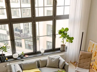 A modern, industrial-style living room featuring a grey sofa, a wooden coffee table, and potted plants.
