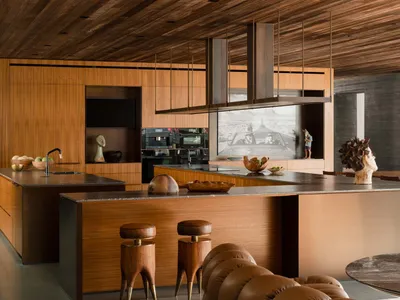 Modern kitchen with wood and metal finishes, featuring a large island and a seating area with stools.