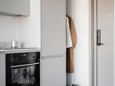 Modern, minimalist kitchen with grey cabinets, black appliances, and neutral decor.