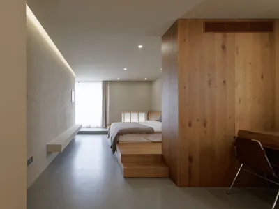 A minimalist bedroom with wooden walls and a bed on a wooden platform.