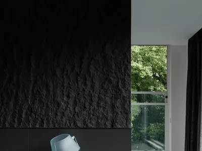 A modern bedroom featuring a glass lamp on a floating nightstand with a textured black wall in the background