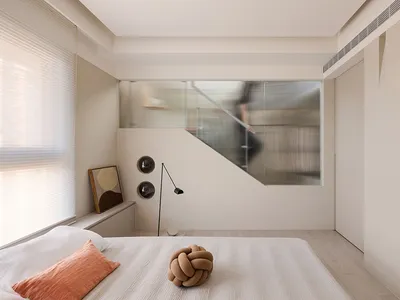 Minimalist bedroom featuring a bed with fabric bedding and a knotted decorative pillow.