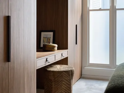 A minimalist bedroom dressng area with wooden paneling and a woven basket on the floor.