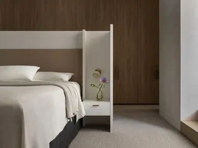 A minimalist bedroom featuring a bed with white bedding, a wooden headboard, and a nightstand with a vase of flowers. The roo