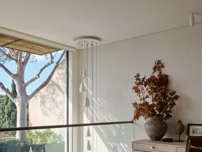 Modern home office featuring a wooden floor, a desk with a plant, and a large window.