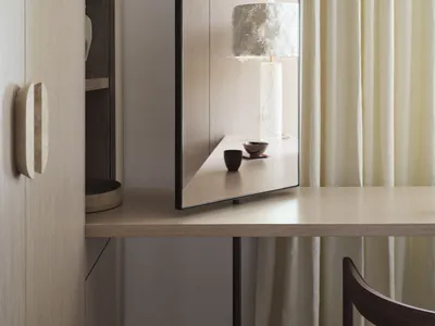 Modern home office with a wooden desk, lamp, and curtain.