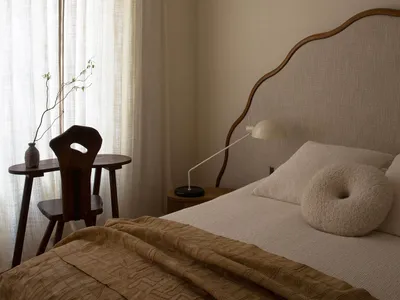 A modern minimalist bedroom featuring soft textiles, wooden furniture, and linen curtains.