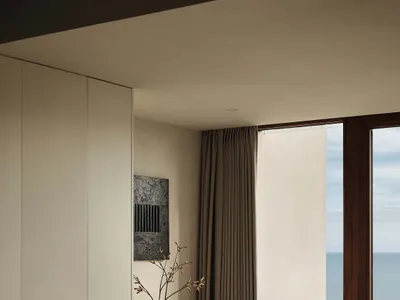 Minimalist bedroom with natural wood furniture and a view of the ocean.