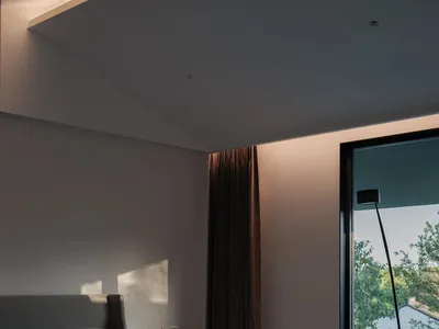 A minimalist bedroom with a gray fabric bed and a modern lounge chair.
