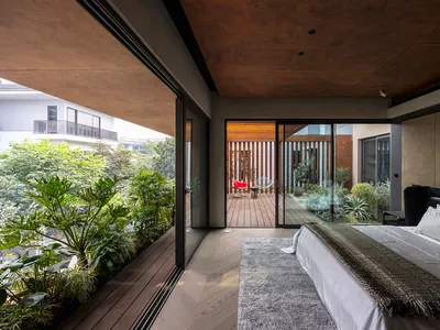 A modern bedroom with a balcony featuring plants and a wooden deck.