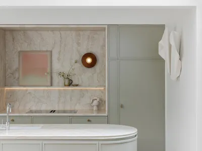 An elegant, minimalist kitchen featuring a marble countertop and backsplash with soft lighting and subtle decorative elements