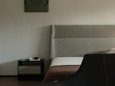 A minimalist bedroom with a gray upholstered bed and nightstand